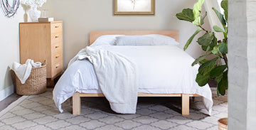Wooden bed with white bedding and a matching chest of drawers.