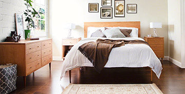 Wooden bed with white linens and matching wooden bedside tables, complemented by a wooden dresser.