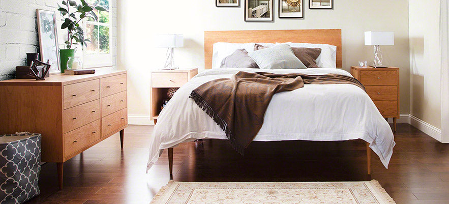 Wooden bed with white linens and matching wooden bedside tables, complemented by a wooden dresser.