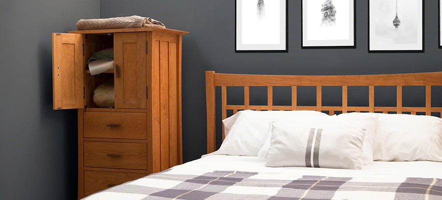 Wooden bed with white and striped bedding accompanied by a matching wooden cabinet.