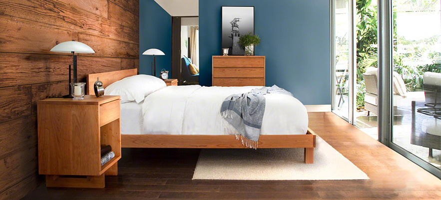 Wooden bed frame with white bedding, accompanied by matching wooden nightstands and lamps.