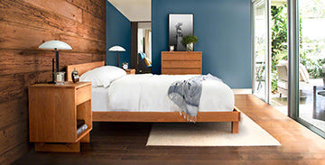 Wooden bed frame with white bedding, accompanied by matching wooden nightstands and lamps.