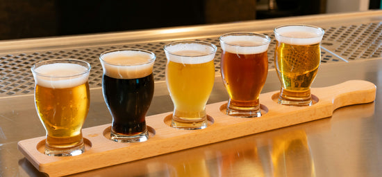 Wooden paddle showcasing five beer glasses, each containing a different style of beer.