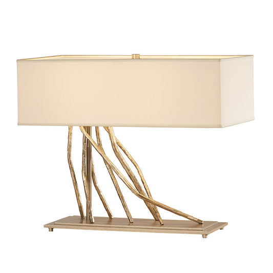 Brindille Table Lamp by Hubbardton Forge featuring a cream shade, dark smoke finish, and gold branch-inspired base.