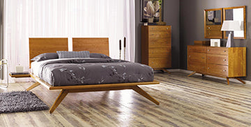 Wooden bed with gray bedding, accompanied by a matching dresser and tall chest.