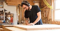 Skilled craftsperson meticulously working on a high-quality wooden furniture piece in a carpentry workshop.