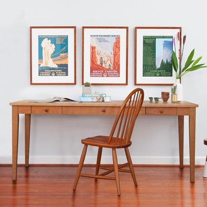 A desk with three framed posters in front of it.