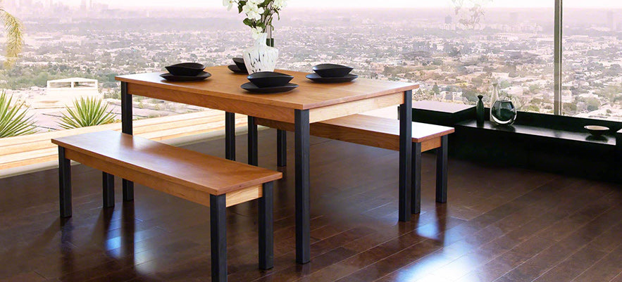 A dining table with two benches in front of a window with a view of the city.