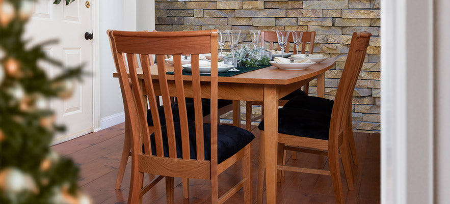 Elegant wooden dining table set with glassware and plates, surrounded by matching chairs.