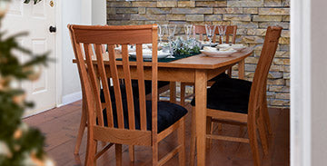 Elegant wooden dining table set with glassware and plates, surrounded by matching chairs.