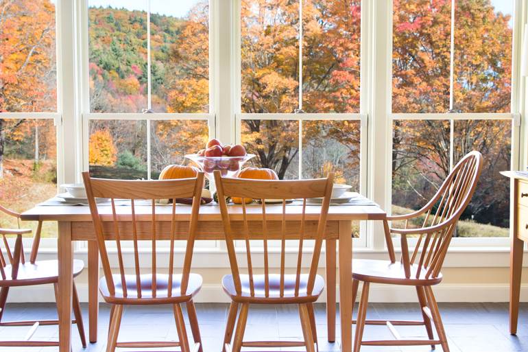 A dining room with a table and chairs in front of a window.