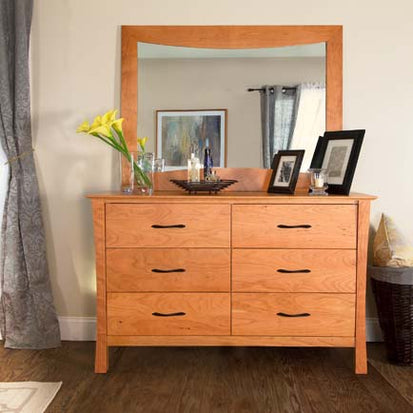 A wooden dresser with a mirror in a room.