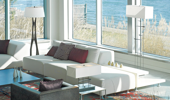 White sofa with a patterned rug and floor lamps in a bright living room.