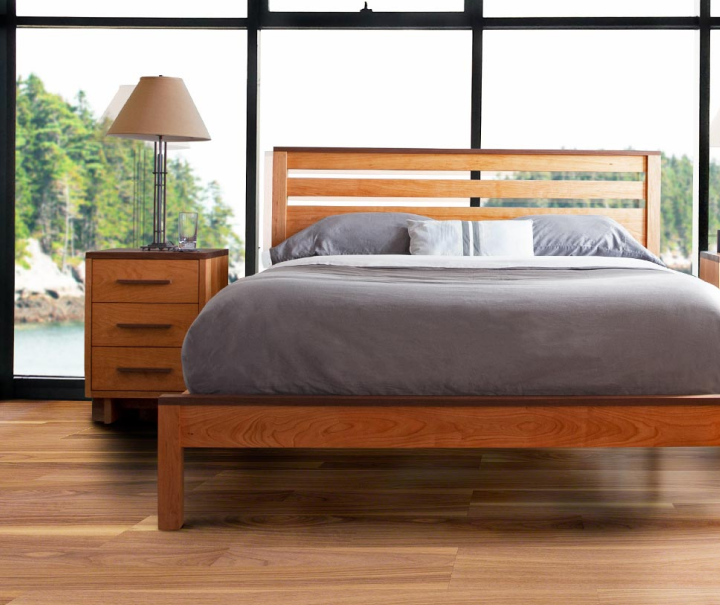 A wooden bed in a bedroom with a view of the ocean.
