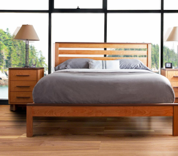 A wooden bed in a bedroom with large windows.