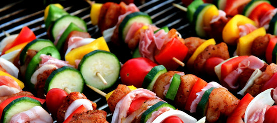 Close-up of a wooden grill cart showcasing grilled skewers with chicken, bell peppers, zucchini, tomatoes, and onions.