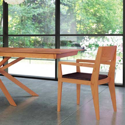 A wooden dining table in a room with large windows.