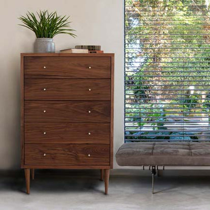 A chest of drawers in a room with a window.