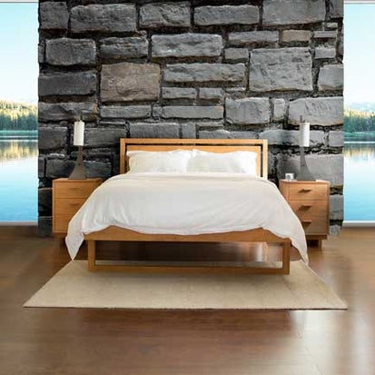 A bedroom with a stone wall and a bed.