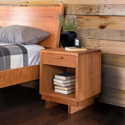 A wooden nightstand with a book on it.