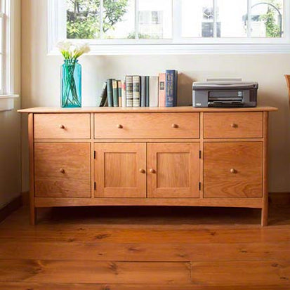A wooden dresser in a room with a window.