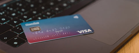 A credit card sitting on top of a laptop.