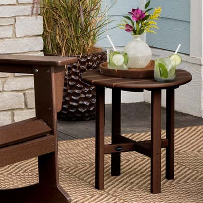 A table with a drink on it and a rocking chair.