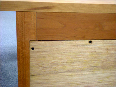 A close up of a wooden desk with holes in it.
