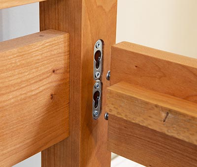 A close up of a wooden bed frame with a metal latch.