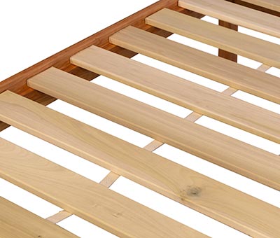 A close up of a wooden bed frame with wooden slats.