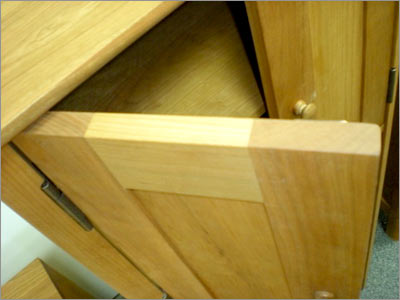 A wooden cabinet with a door open.