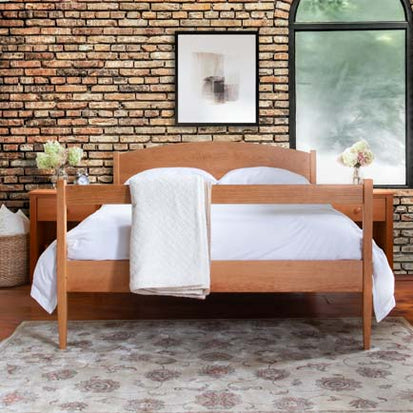 A bedroom with a brick wall and a wooden bed.