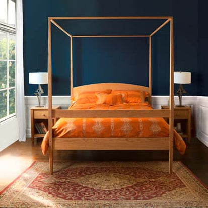 A four poster bed in a bedroom with blue walls.