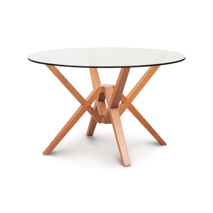 A round table with a glass top and wooden legs.