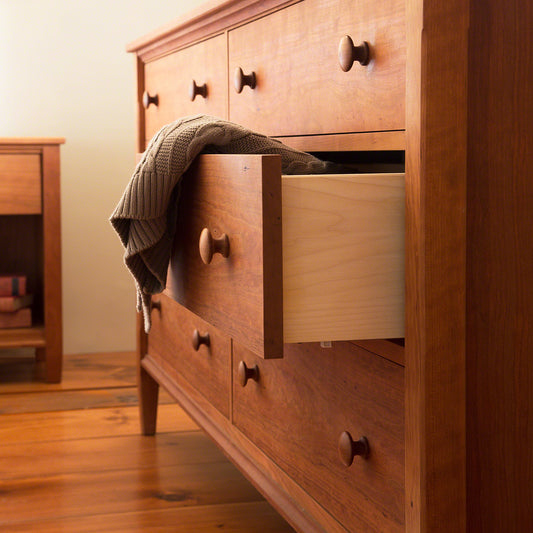 A wooden dresser with drawers open on a wooden floor.
