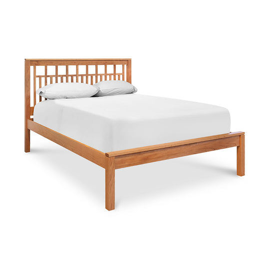 A wooden bed frame with white sheets on it.