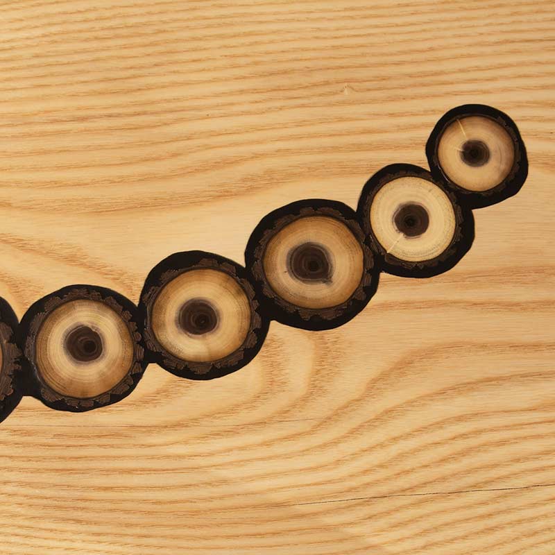 A piece of wood with black circles on it.